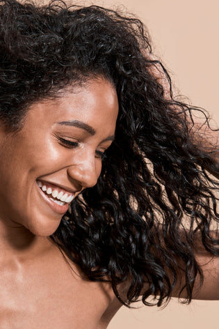 beautiful young woman with dark curly hair smiling