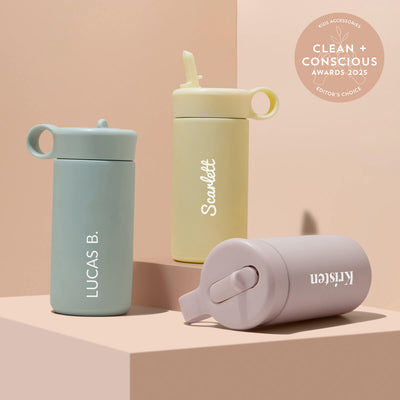 Three insulated kids water bottle with names printed on them against a beige background, featuring the 'Clean + Conscious Awards 2025' badge.