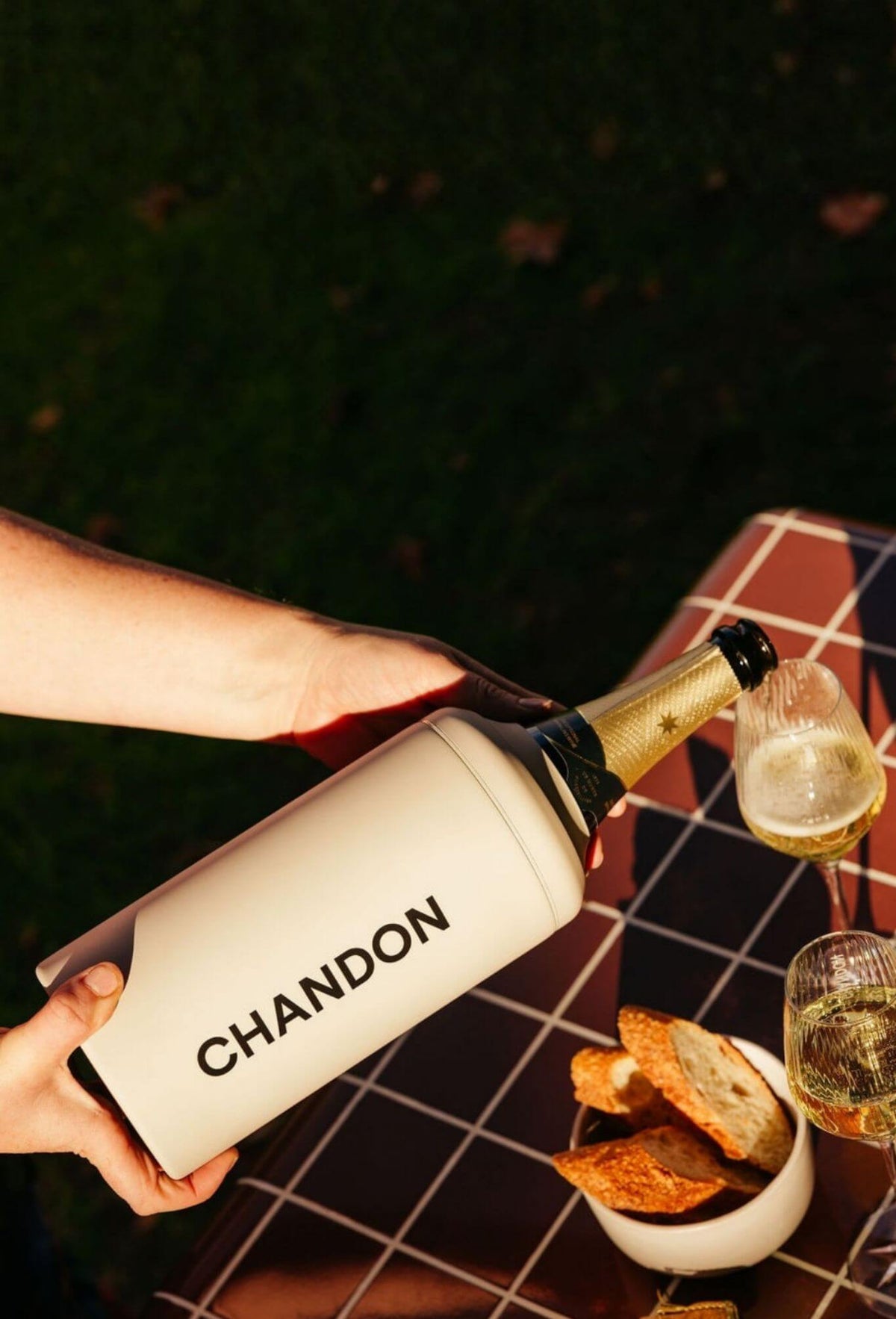 Beysis stone stainless steel wine cooler branded with a company logo, pouring sparkling wine into a glass on a tiled table