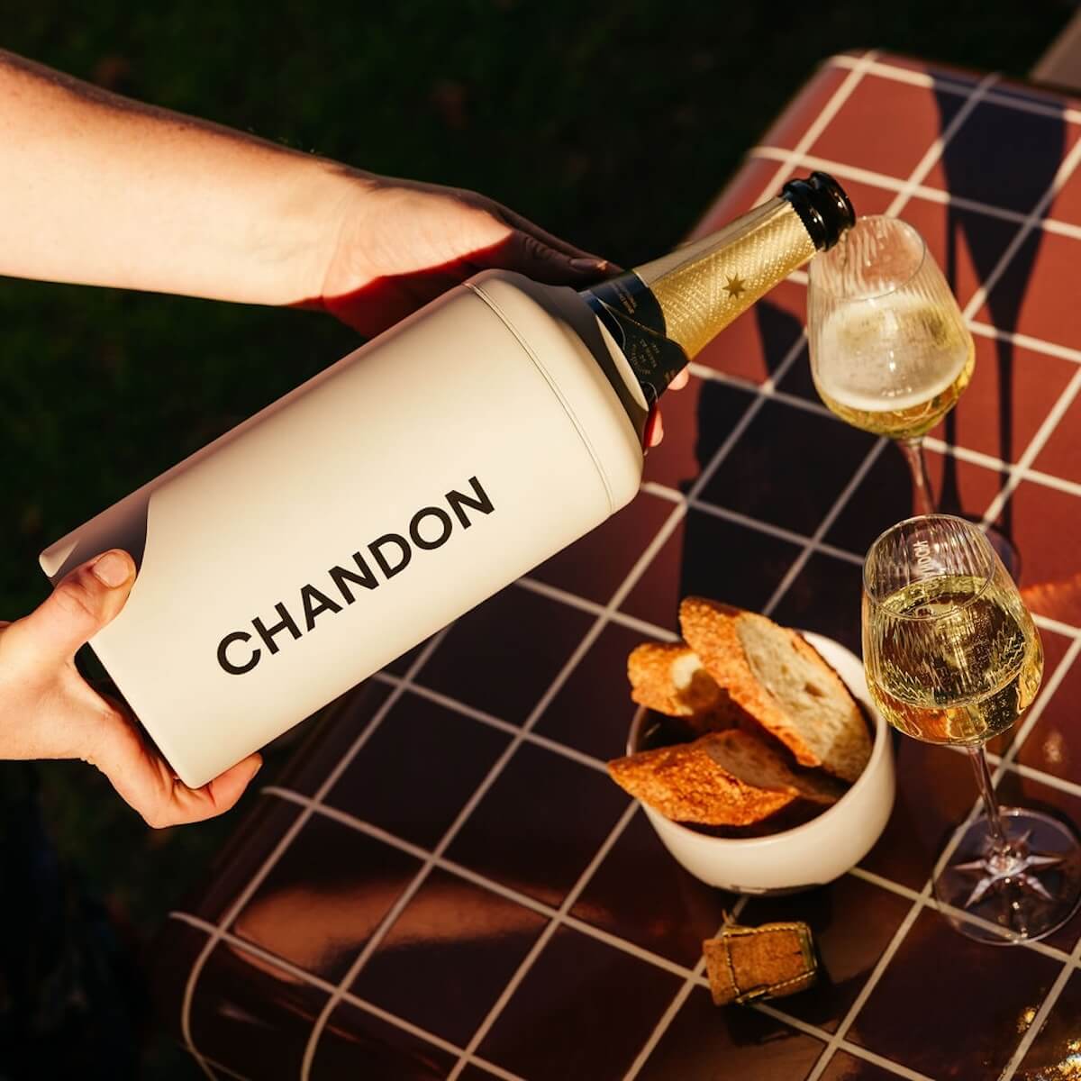 Beysis stone stainless steel wine cooler branded with a company logo, pouring sparkling wine into a glass on a tiled table